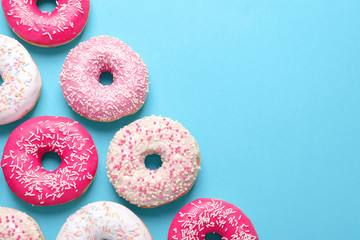 Delicious glazed doughnuts on color background, top view