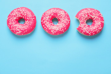Delicious glazed doughnuts on color background, top view