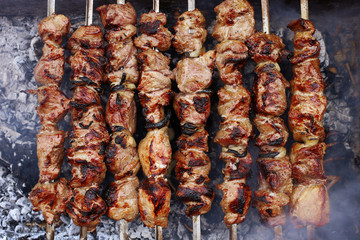Barbecue in nature in summer. Pork meat in the smoke on the coals, healthy food, closeup, top view.