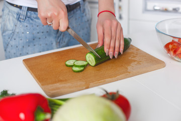 Young attractive woman cooking salad indoors at the kitchen