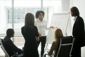 Serious african female leader or coach gives presentation of new marketing plan at sales team...