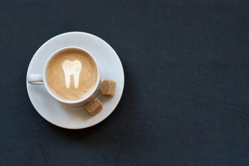 Cup of coffee with milk, cane sugar and tooth sign on dark background. Top viewю Copy space