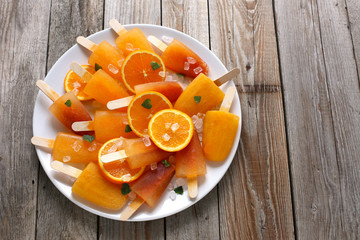 Orange ice pops on old wooden table