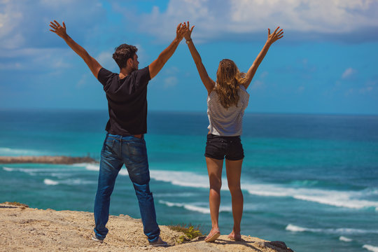 Couple with arms wide open enjoying the ocean / sea view.