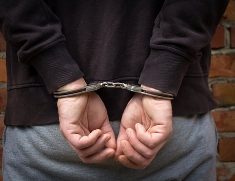 Criminal in handcuffs arrested for crimes.Close-up of a criminal hand in handcuffs