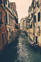 Romantic view of a canal of Venice with some boats and a sunny light, Italy