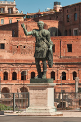 Fototapeta na wymiar Rome, Bronze statue of emperor Caesar Nervae Trajan, Forum of Caesar Nervae Trajan in the background