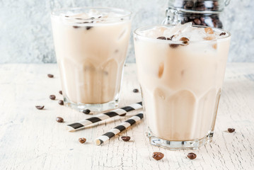 Summer cold Iced coffee frappe with milk and ice cubes, light concrete background copy space