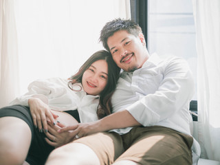 Obraz premium Asian man husband take care of his pregnant wife.Beautiful pregnant woman and her handsome husband are smiling while spending time together.