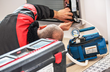 Technician vacuum pump evacuates and checking new air conditioner.