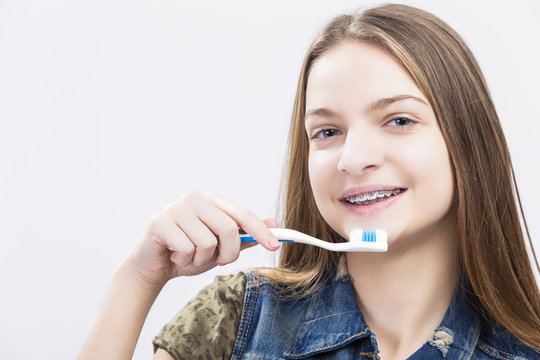 Dental Health Concepts. Portrait of Smiling Caucasian Teenage Girl with Teeth Brackets. Posing with Toothbrush