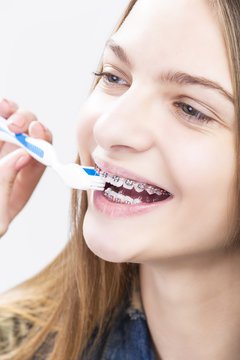 Dental Health Concepts. Closeup Portrait of Blond Caucasian Teenage Girl Wearing Teeth Braces. Brushing Her Teeth with Manual Brush.