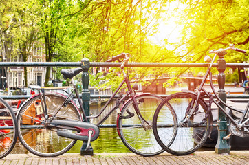 Fototapeta na wymiar Bicycles on the bridge in Amsterdam, Netherlands against a canal with a sunlight. Amsterdam postcard. Tourism concept.
