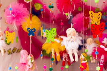 Handmade colorful dolls, butterflies and other toys hanging on threads in flea market stand