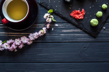 Obraz na płótnie Canvas tea, sakura, sushi on a black background