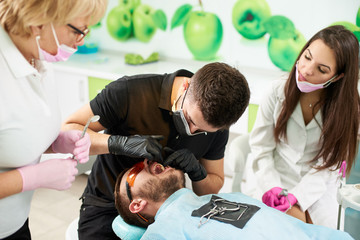 Assistant dentist in the presence of a doctor prepares the patient to remove the tooth . Modern clinic with new technologies