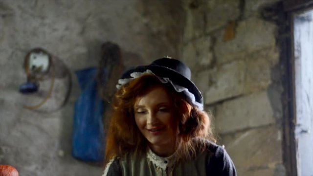 Red-haired girl with a big pumpkin in the hut. Fairy-tale character. Magic of miracles