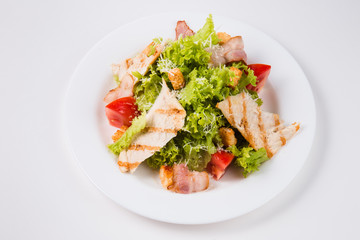 salad with bacon, tomatoes and croutons on a white plate