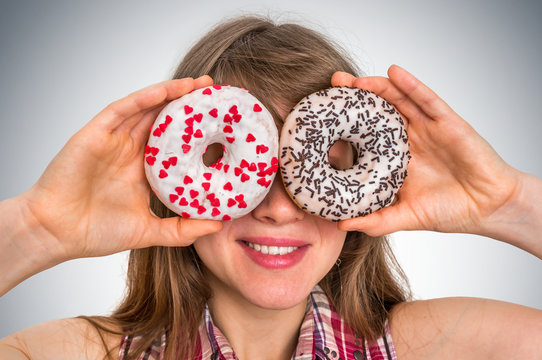Attractive woman is holding donuts against her eyes