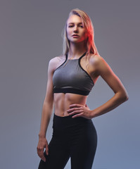 Sexy slim blonde girl in a sportswear posing in a studio.