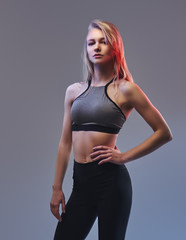 Sexy slim blonde girl in a sportswear posing in a studio.