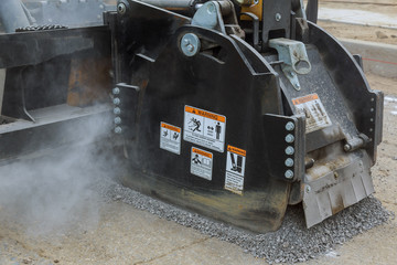 Road work with an asphalt road milling machine removing old pavement from a street surface