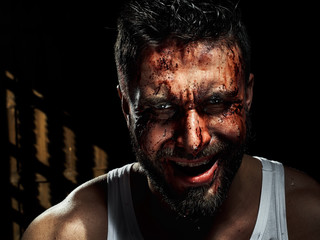 A strong, a serious, muscular man in a white t-shirt is worth and looks in camera. He's got the beard on the face and different emotions