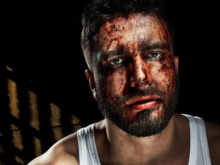 Obraz premium A strong, a serious, muscular man in a white t-shirt is worth and looks in camera. He's got the beard on the face and different emotions