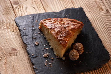 A piece of apple pie with grated chocolate near chocolate truffle candies. Selective focus and small depth of field.