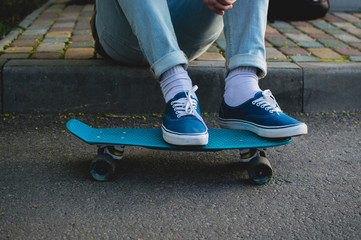 Man in blue canvas shoes standing on the blue plastic penny skateboard. The concept of city travelling, vlogging, modern lifestyle