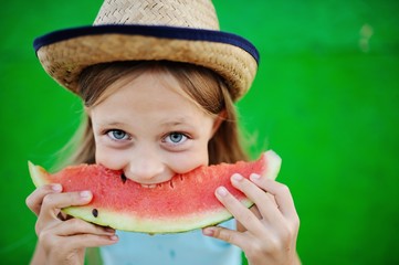 baby girl greedily eating ripe watermelon on a green background