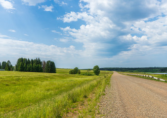 Road passing through the field in rural areas in Russia, in Udmurtia in summer
