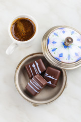 Top view of Handmade chocolate candy with purple splashes on plate with cup of coffee
