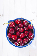 Cherry in old enamel mug, white wood table background
