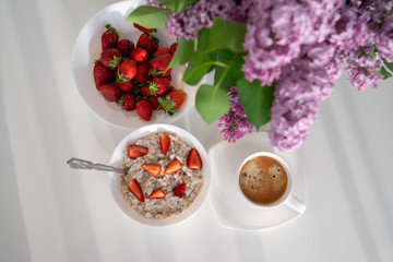 Healthy breakfast, oatmeal, coffee with lilac on a white background