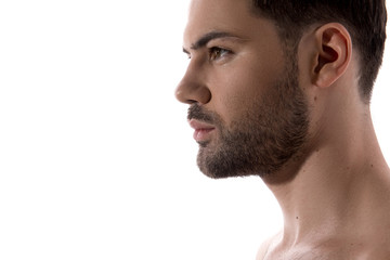 Beauty concept. Close up of profile of young bearded guy is standing and looking forward confidently. Isolated and copy space in the left side