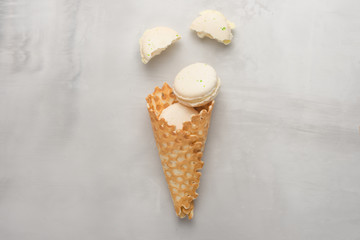 Flat-lay sweet cone wafers with white macaroons on a light background, top view. The concept of spring or summer mood