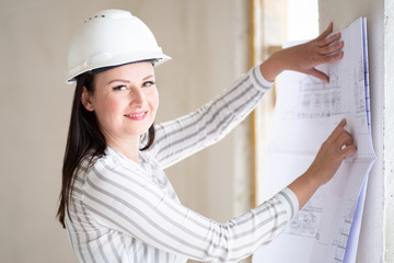 Junge Architektin auf einer Baustelle lächelt sympathisch in die Kamera 