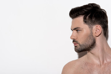 Profile of attractive bearded naked guy is standing and looking aside wistfully. Copy space in the...