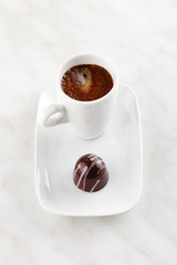 Handmade chocolate candy with purple splashes on plate with cup of coffee