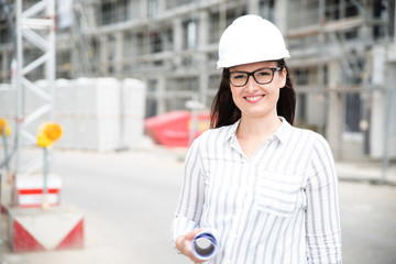 Frau auf einer Baustelle mit Bauhelm und Plänen 