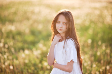 Fototapeta na wymiar portrait of beautiful young caucasian girl wearing white shirt in summer sunset field outdoors