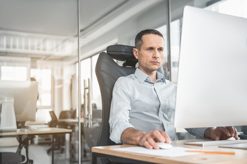 Portrait of concentrated businessman typing in keyboard of computer. Focused employee using gadget concept