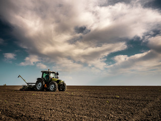 Obraz premium Farmer seeding, sowing crops at field. Sowing is the process of planting seeds in the ground as part of the early spring time agricultural activities.