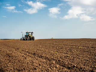 Obraz premium Farmer seeding, sowing crops at field. Sowing is the process of planting seeds in the ground as part of the early spring time agricultural activities.