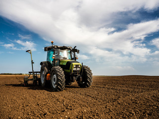 Fototapeta premium Farmer seeding, sowing crops at field. Sowing is the process of planting seeds in the ground as part of the early spring time agricultural activities.