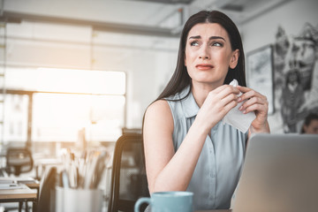 Portrait of crying lady looking away while working in modern office. Sad employer concept