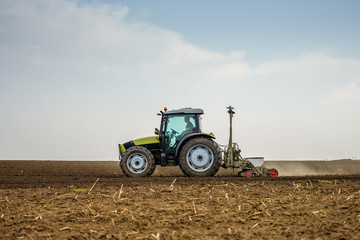 Obraz premium Farmer seeding, sowing crops at field. Sowing is the process of planting seeds in the ground as part of the early spring time agricultural activities.