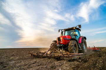 Obraz premium Tractor cultivating field at spring