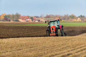 Fototapeta premium Farmer plowing stubble field